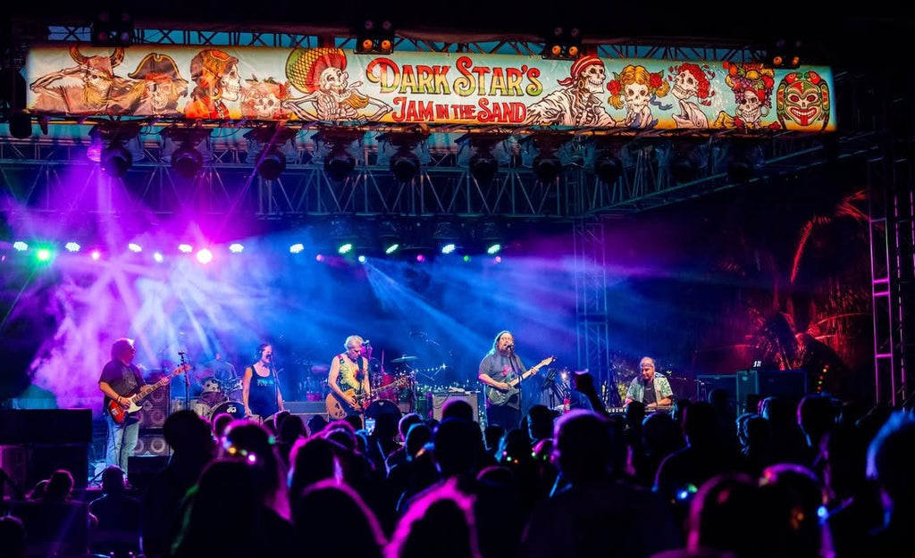 Dark Star Orchestra performing on stage at Dark Star's Jam in the Sand. Purple and blue stage lighting looking over the crowd at the band on stage.
