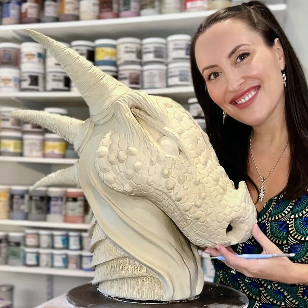Jess Burbridge posing in her studio with a dragon sculpture