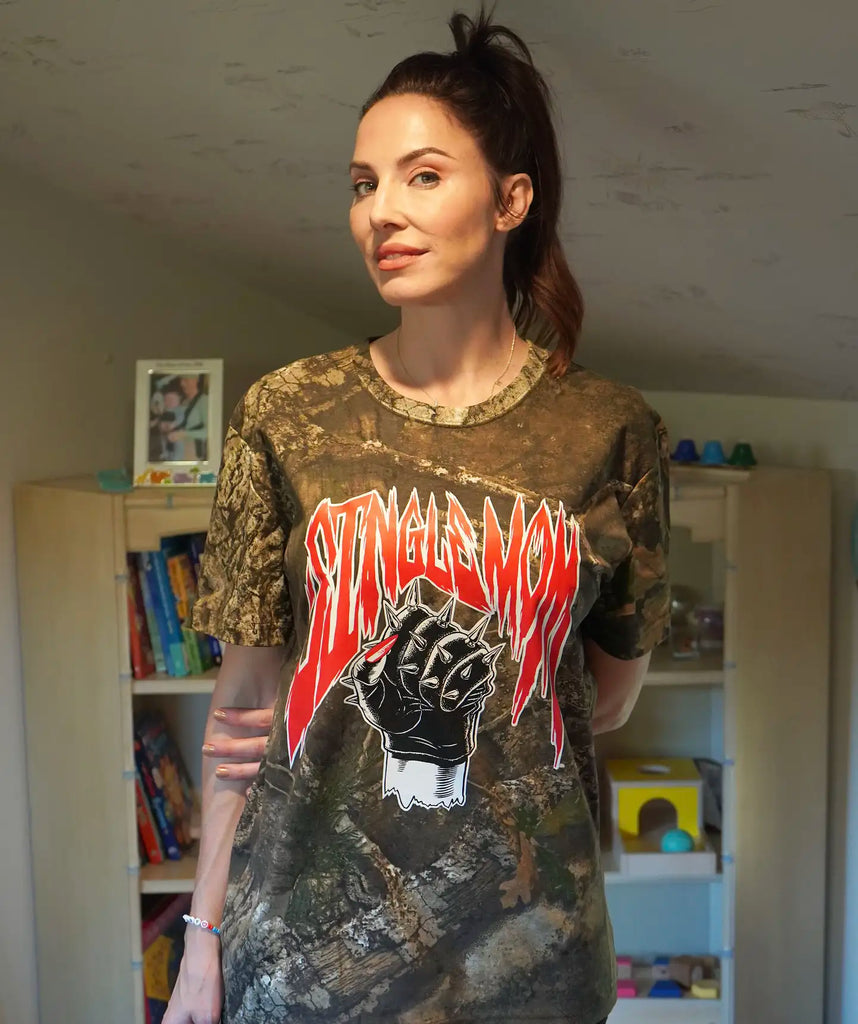 A photo of Whitney Cummings posing in her woodland camo Single Mom t-shirt.