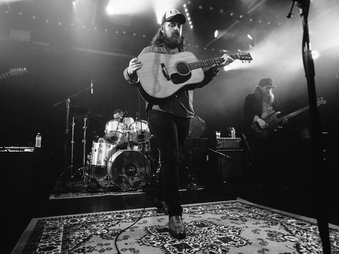 Drayton Farley performing on stage holding acoustic guitar