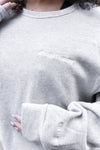 Close-up detail of Team Tammy Crew Ultra Cozy sweatshirt in light heather grey, showing white embroidered text on chest and sleeve cuff. Fleece-lined fabric with ribbed collar and cuffs visible.