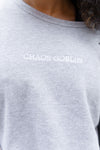 Goblin Crew: Ultra Cozy sweatshirt in light heather gray featuring white embroidered CHAOS GOBLIN text across the chest. Close-up detail shot showing the clean, minimalist design and premium cotton blend fabric texture.