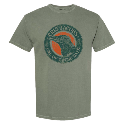 Olive green t-shirt featuring a circular graphic design with a raven silhouette against an orange background, surrounded by text reading 