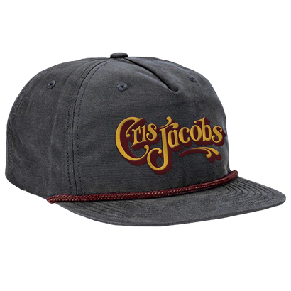 Charcoal gray snapback hat with Cris Jacobs script logo in gold and red. Flat bill with burgundy rope detail. Structured grandpa-style cap with pinch front and 5-panel design. Custom nylon material for durability and style.