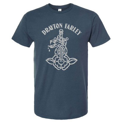 Indigo blue t-shirt featuring a light gray print of a decorative dagger piercing a stylized flower design, with the text 