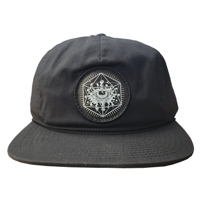 Black unstructured 5-panel hat with rope detail on visor, featuring ODDS 'Life Force' circular patch with intricate geometric and eye design. Snapback closure visible, showcasing classic style and unique branding.