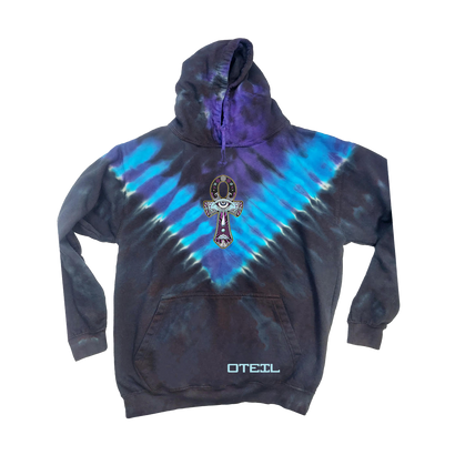 Tie dye hoodie with blue and purple V-pattern, featuring large Ankh symbol design on front and small Oteil logo on pocket. Vibrant colors and unique hand-dyed fabric create eye-catching statement piece.