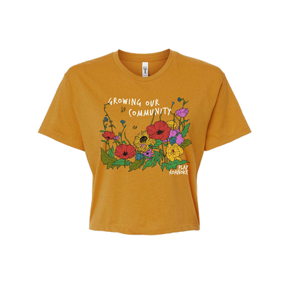 Play Roanoke Growing Our Community Graphic on a gold crop t-shirt