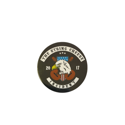 2017 Eagle Pin featuring a fierce bald eagle head on a black circular button with The String Cheese Incident band name, crossed acoustic guitars, stars, and the year 2017 in a patriotic emblem design