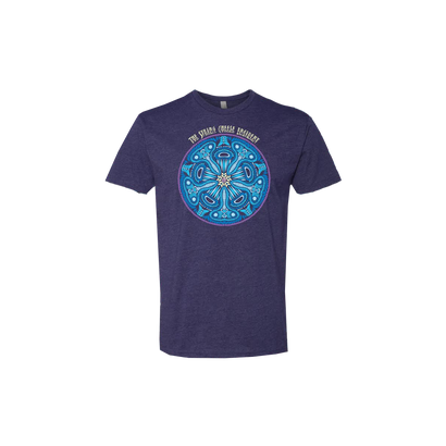 Into the Blue Tee featuring a vibrant circular mandala design in bright turquoise and white against a navy blue t-shirt. The intricate pattern showcases symmetrical geometric shapes forming a mesmerizing kaleidoscope effect with The String Cheese Incident text arching above the design.