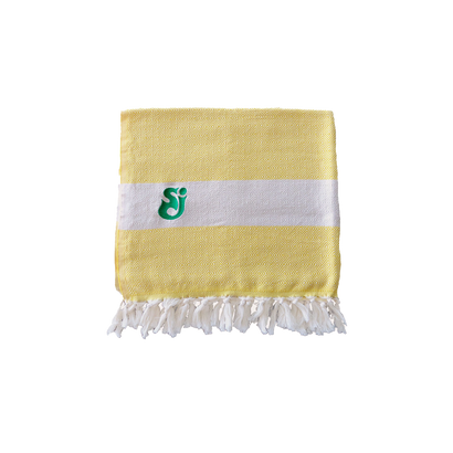 SCI Throw/Towel featuring a soft yellow and white woven pattern with green embroidered logo in corner, adorned with white fringe tassels along the edge. Large beach or couch blanket displaying elegant striped design.