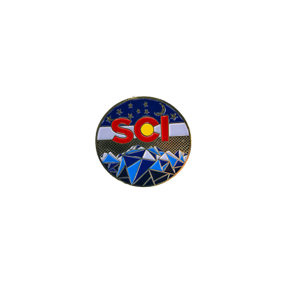 Mountain Pin featuring circular design with SCI logo incorporating Colorado flag colors, geometric blue mountain range against starry night sky background, black border trim, limited edition collector's item